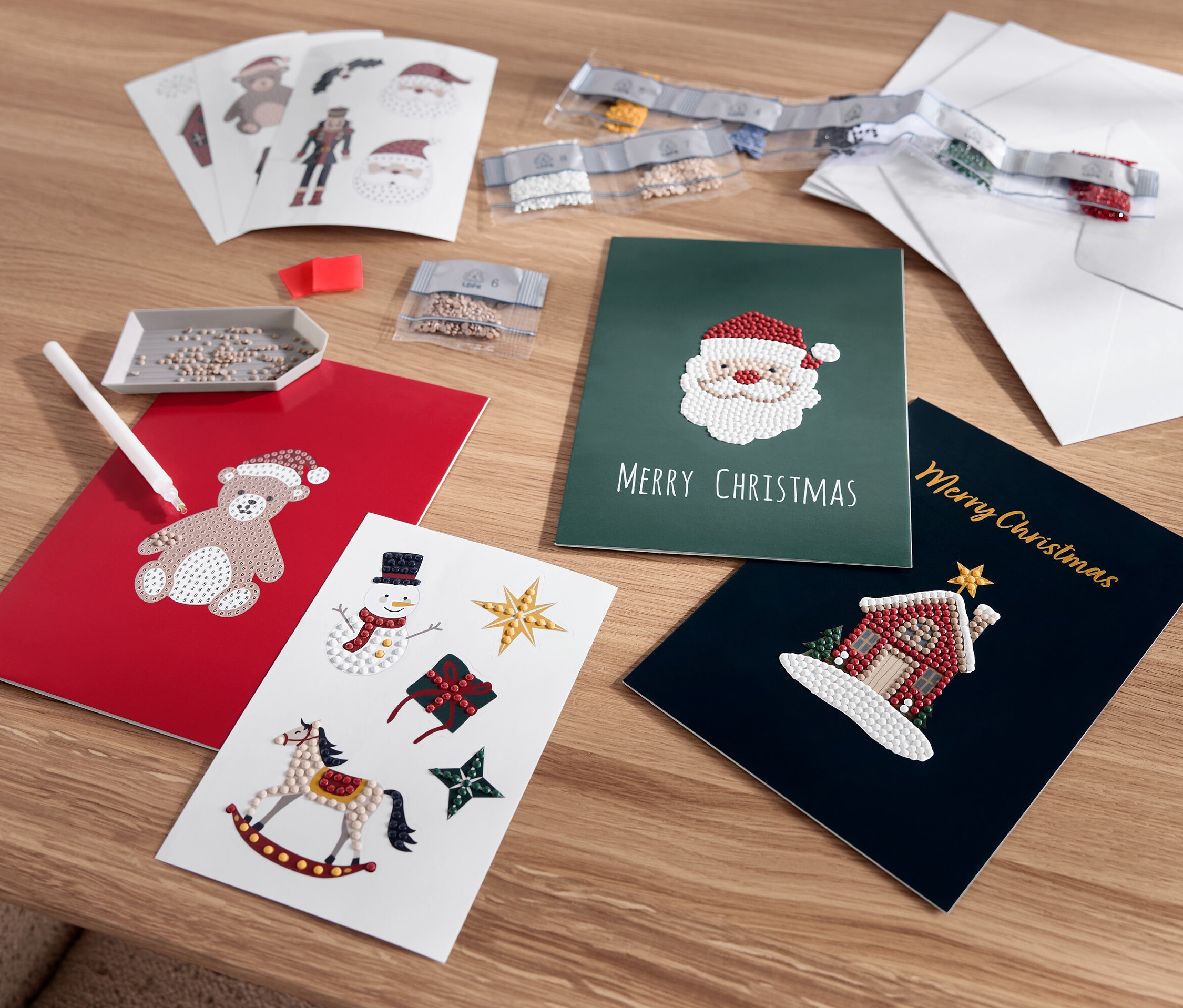 Rozložené vianočné pohľadnice s motívmi medvedíka, Santa Clausa, snehuliaka a domu.