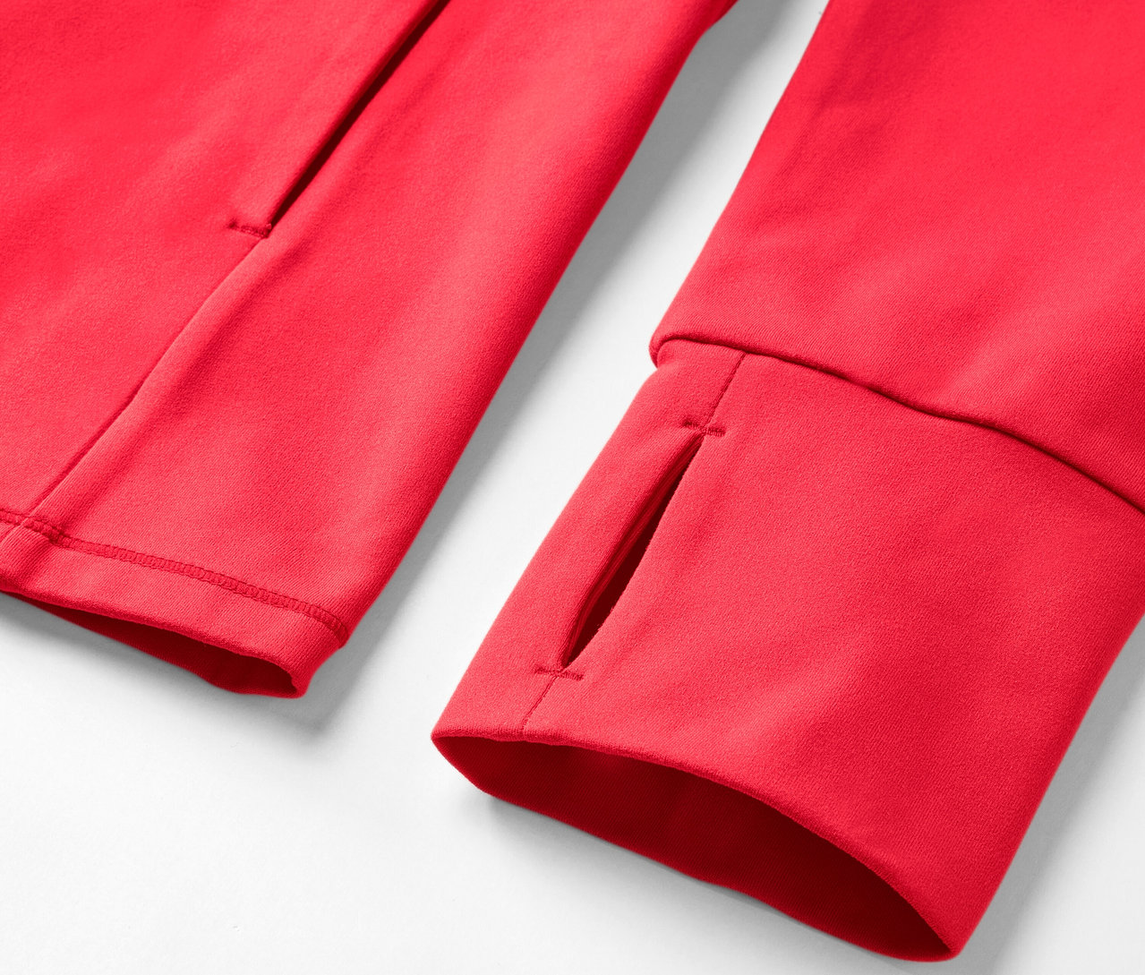 Detail červenej mikiny s otvorom na palec a vreckom.