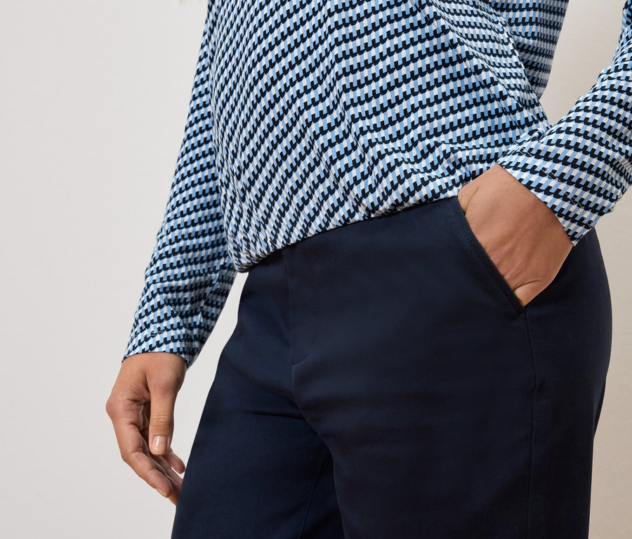 Čiastočný pohľad na osobu s rukou vo vrecku nohavíc a v modro-bielom tope.