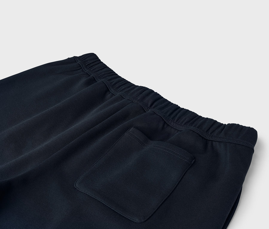 Detailný záber na tmavomodré tepláky s elastickým pásom a zadným vreckom.