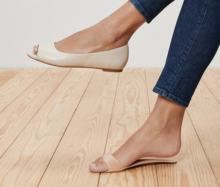 Nohy ženy v džínsoch, jedna noha v krémovej balerínke s otvorenou špičkou a druhá v sandáli s remienkom. Vložky do topánok so stielkou, 1 pár, sú v sandáli.