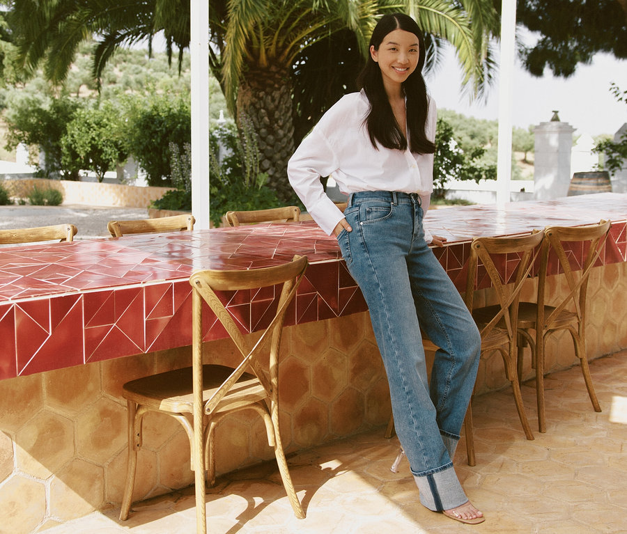 Žena pózuje opretá o barový pult vonku a má na sebe svetlomodré džínsy Angels »Lara« rovný strih Turn Up.