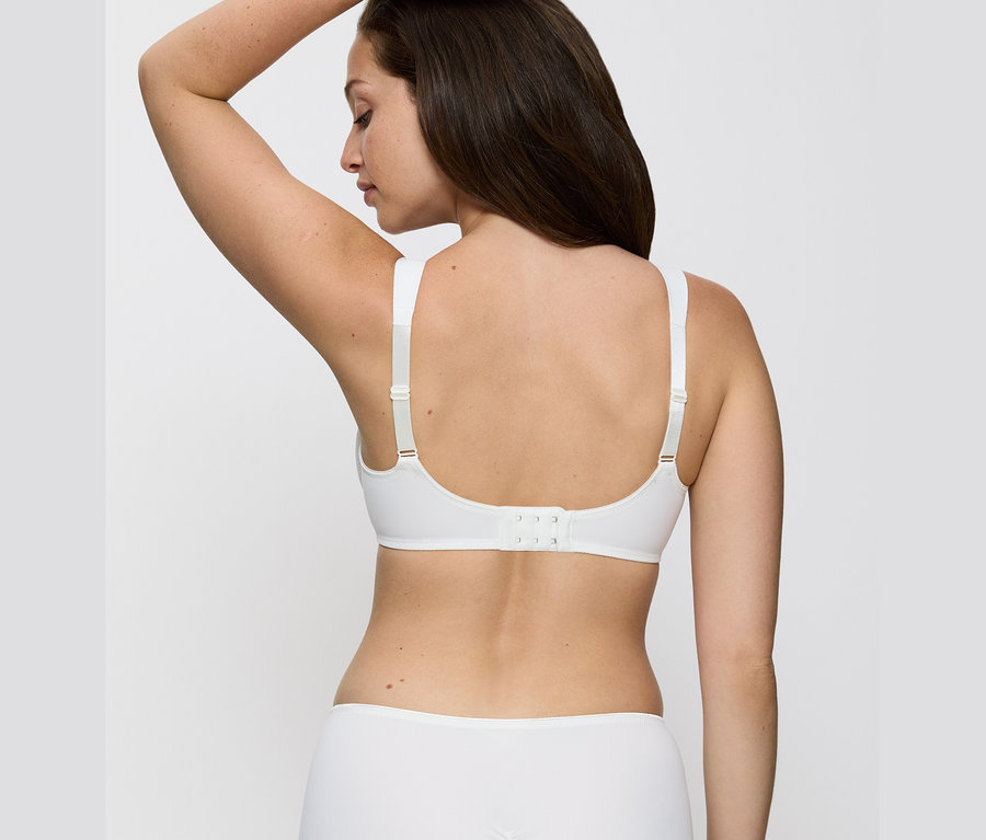 Zozadu je vidieť žena s hnedými vlasmi, ktorá má na sebe vanilkovú podprsenku Triumph Essential »Minimizer W X«.