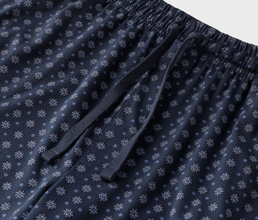 Detailný záber na tmavomodré pyžamové nohavice s kvetinovým vzorom so šnúrkou.