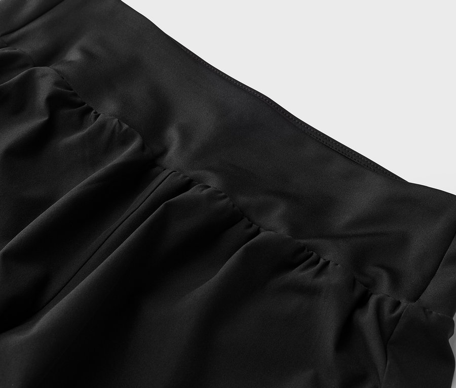 Detailný záber na čiernu látku s detailmi riasenia v páse.