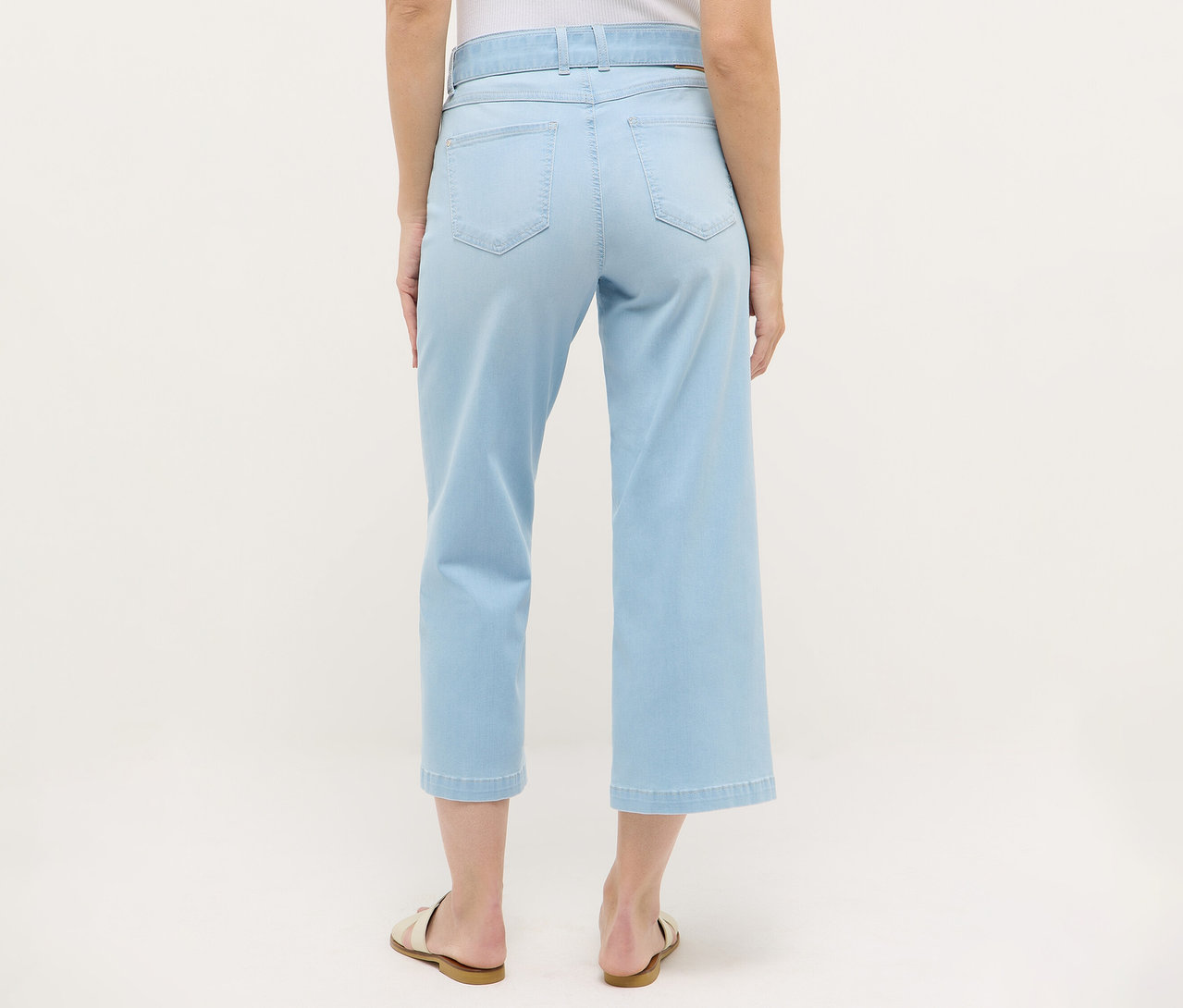 Pohľad zozadu na ženu nosiacu Angels Denim »Linn City« skrátený strih, vybielené modré džínsy a sandále.