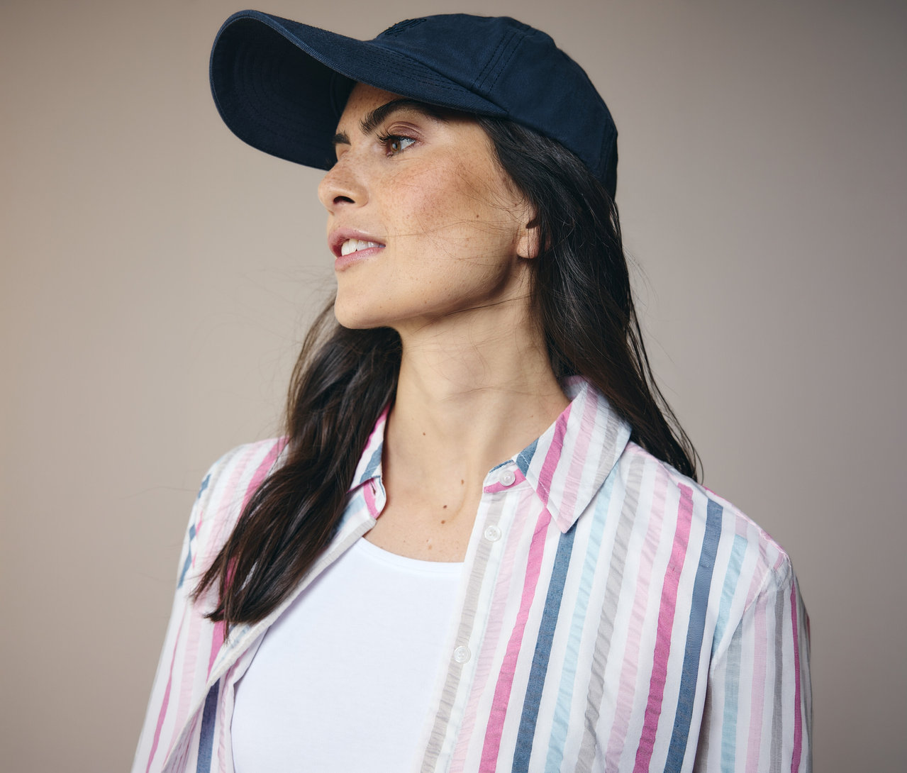 Žena v tmavomodrej šiltovke a pásikavá košeľová blúzka CECIL, pozerá sa doľava.