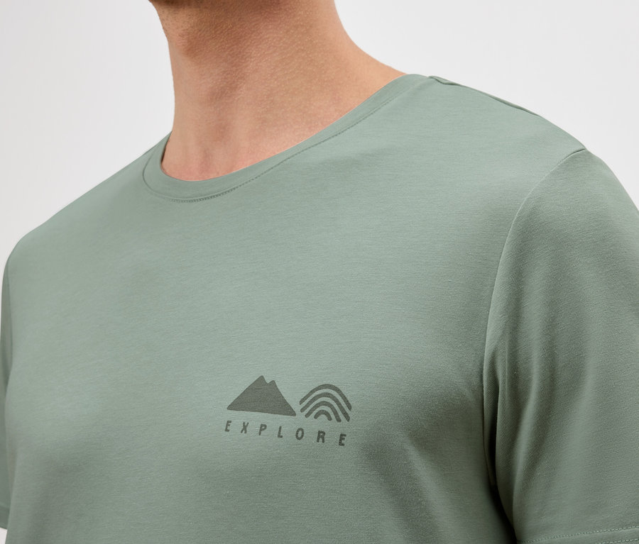 Detail muža v svetlozelenom tričku s malým logom "Explore".