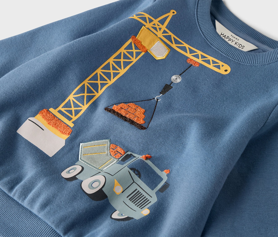 Na modrej mikine je zobrazený žltý žeriav stojaci nad nákladným autom s kolesami.