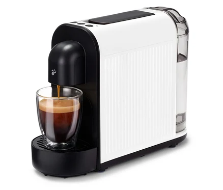 Kávovar Cafissimo now white plní šálku kávou. Kávovar je biely s čiernymi akcentmi a priehľadnou nádržkou na vodu.