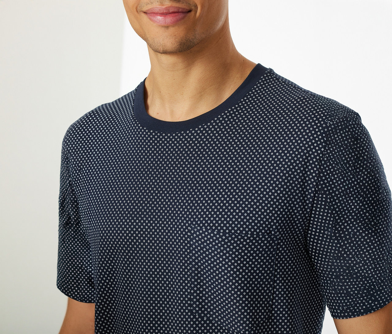 Muž má na sebe krátky pyžamový set SCHIESSER, ktorý pozostáva z modrého trička s krátkym rukávom s bodkovaným vzorom.