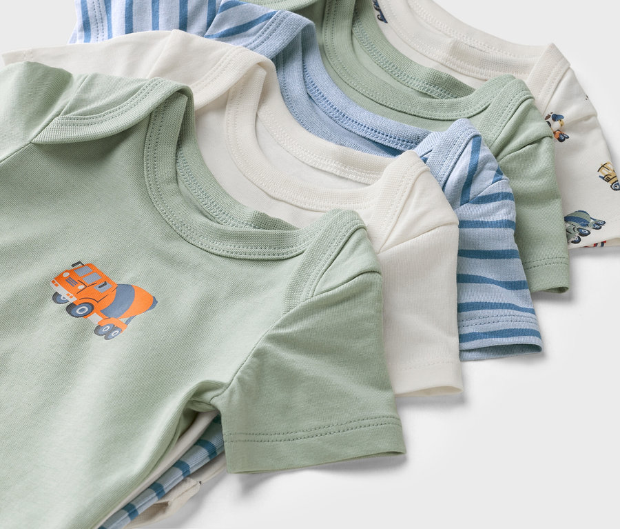 Detailný záber na dojčenské body s krátkym rukávom v rôznych farbách a vzoroch, vrátane zeleného body s motívom domiešavača betónu.