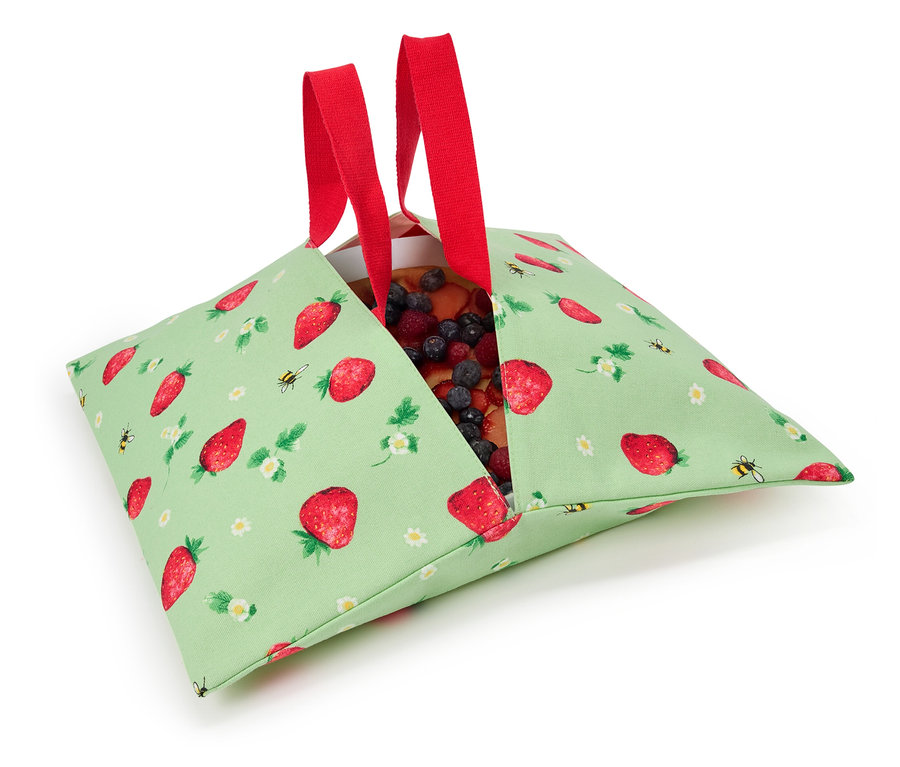 Jahodový koláč v zelenej látkovej taške s jahodovým vzorom a červenými rúčkami.