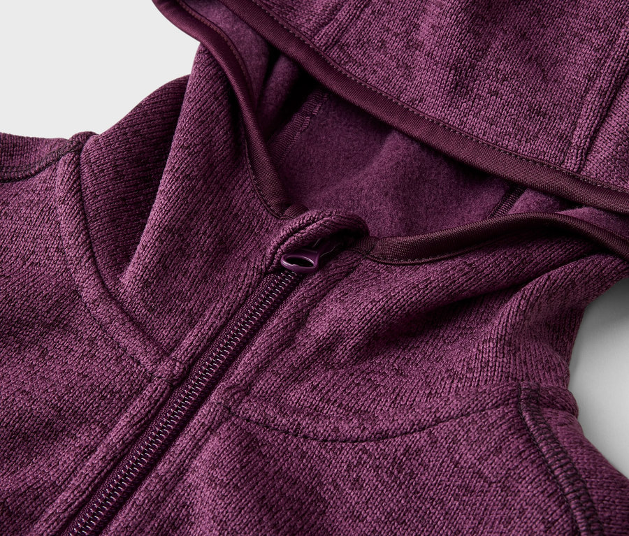 Detailný záber na čiastočne rozopnutú bordovú mikinu s kapucňou na zips.