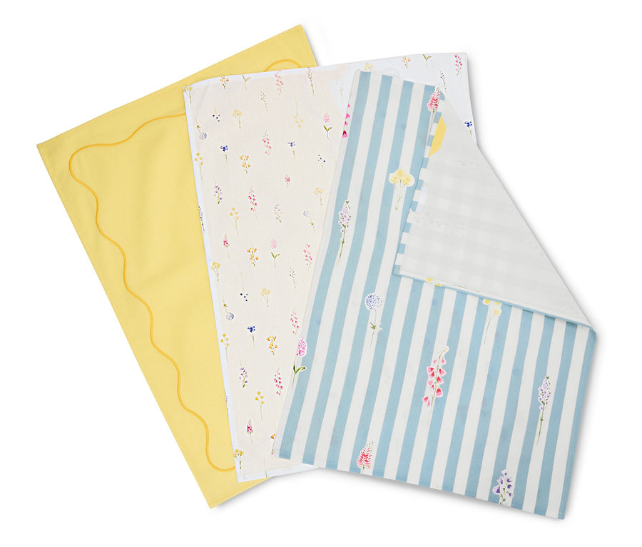 Tri utierky ležia na sebe: žltá so zvlneným okrajom, krémová s kvetinovými vzormi a modro-biela pruhovaná s kvetmi.