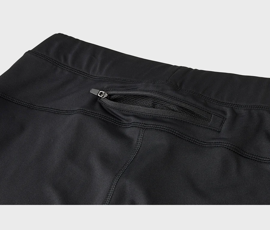 Detail čierneho športového oblečenia s vreckom na zips na zadnej strane, cez ktoré je viditeľná sieťovaná podšívka.