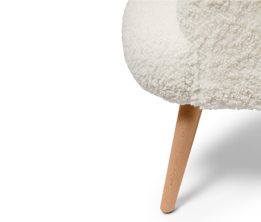 Detail plyšového kresla s drevenou nohou.