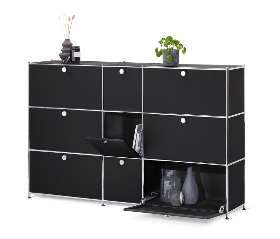 Čierna komoda »CN3« s 9 výklopnými dvierkami, z ktorých jedna je otvorená a odhaľuje knihy a dvoje sú otvorené a odhaľujú vázy.