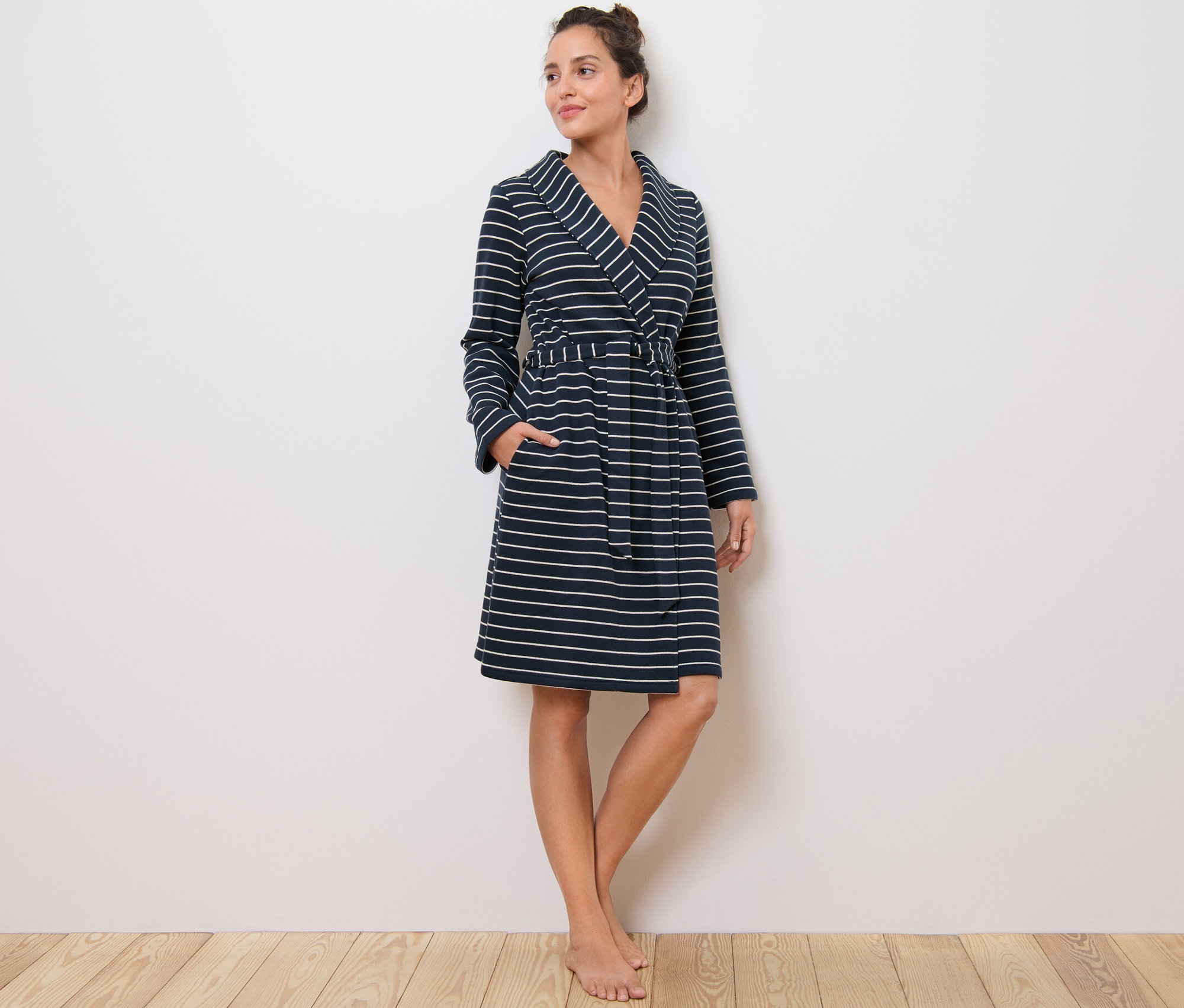 Žena stojí a má na sebe župan s prúžkami.