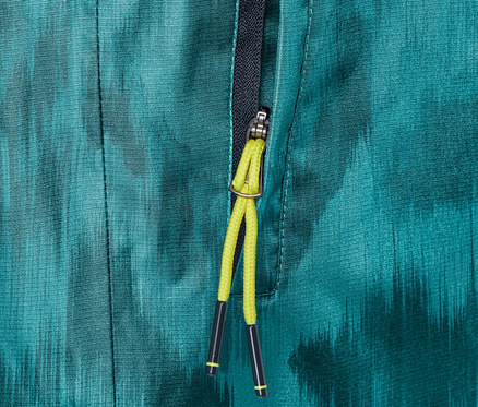 Detailný záber na nohavice do dažďa s celoplošnou potlačou a čiastočne rozopnutým zipsom.