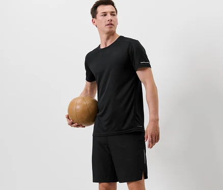 Muž drží basketbalovú loptu a má na sebe čierne funkčné tričko.