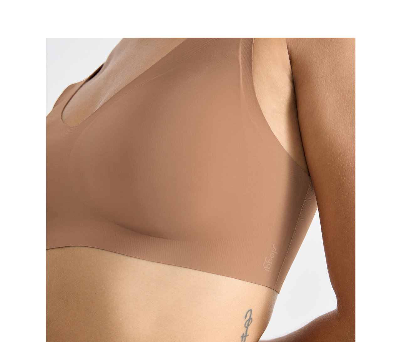 Zblízka osoba v braletke sloggi ZERO Feel 2.0 vo farbe nostalgic brown, s tetovaním na boku.