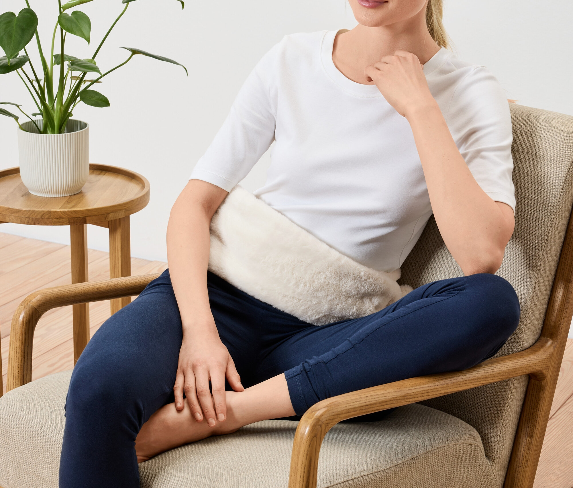 Žena sedí v kresle s hrejivým vankúšikom na bruchu.