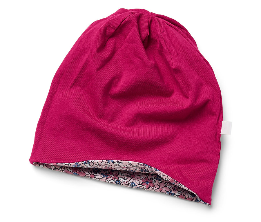 Ružová čiapka s kvetinovou podšívkou leží na bielom pozadí.