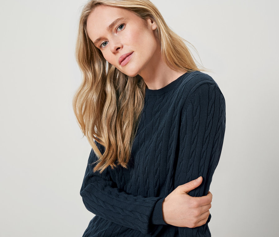 Blondínka má na sebe tmavomodrý pletený sveter.