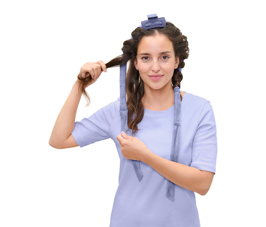 Žena si natáča vlasy pomocou modrého natáčania na vlasy.