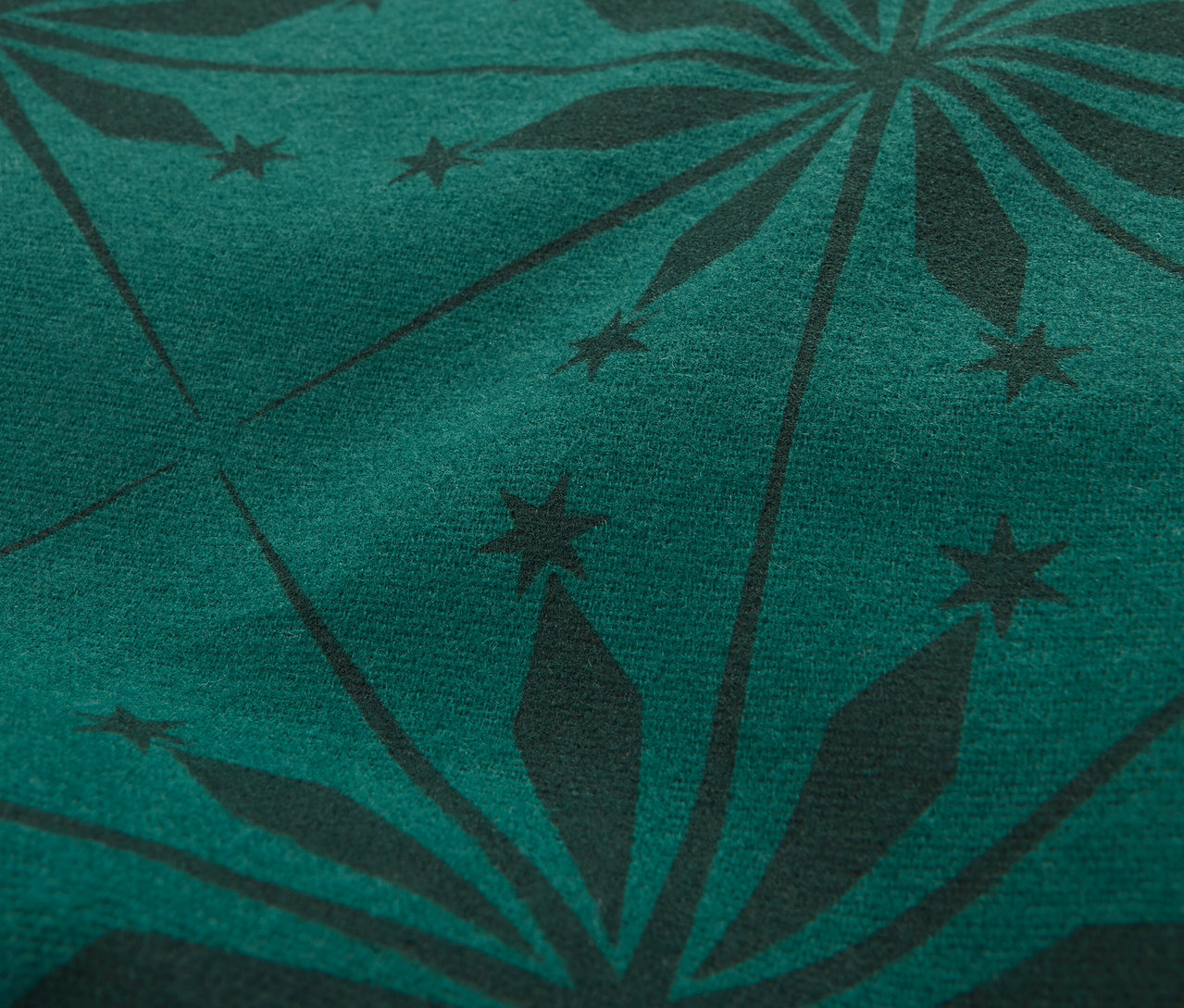 Detailný záber na tmavozelenú látku s čiernym vzorom hviezdic.