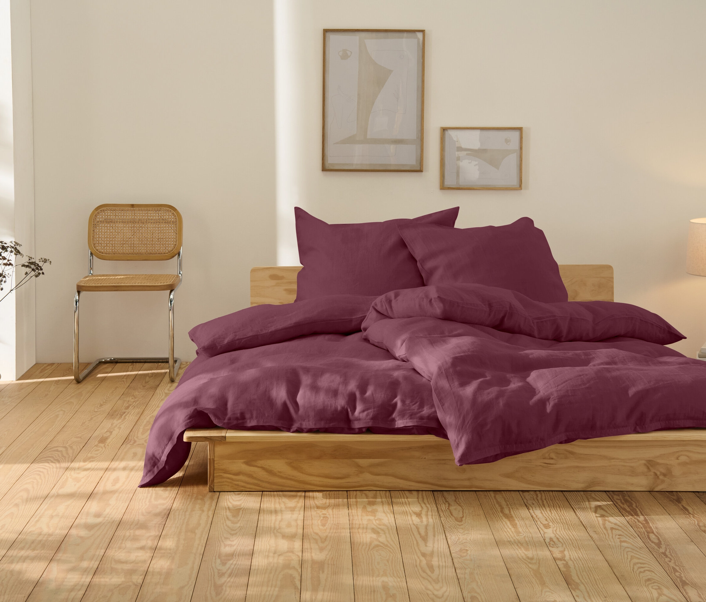 Posteľ s ľanovou posteľnou bielizňou bobuľovej farby, štandardnej veľkosti.