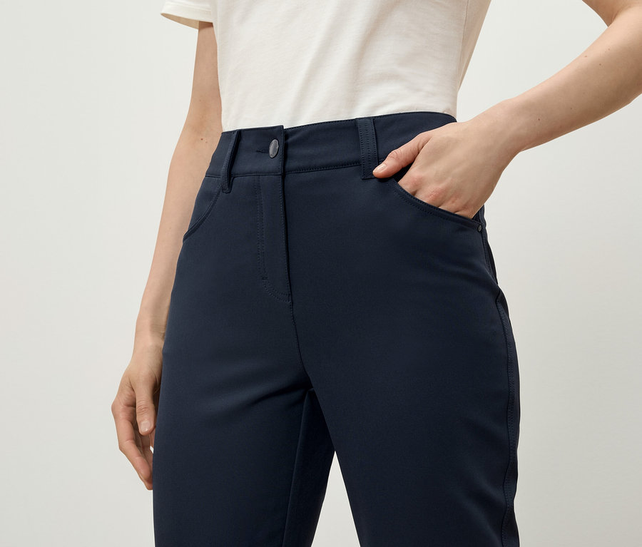 Žena má ruku vo vrecku tmavomodrých nohavíc.