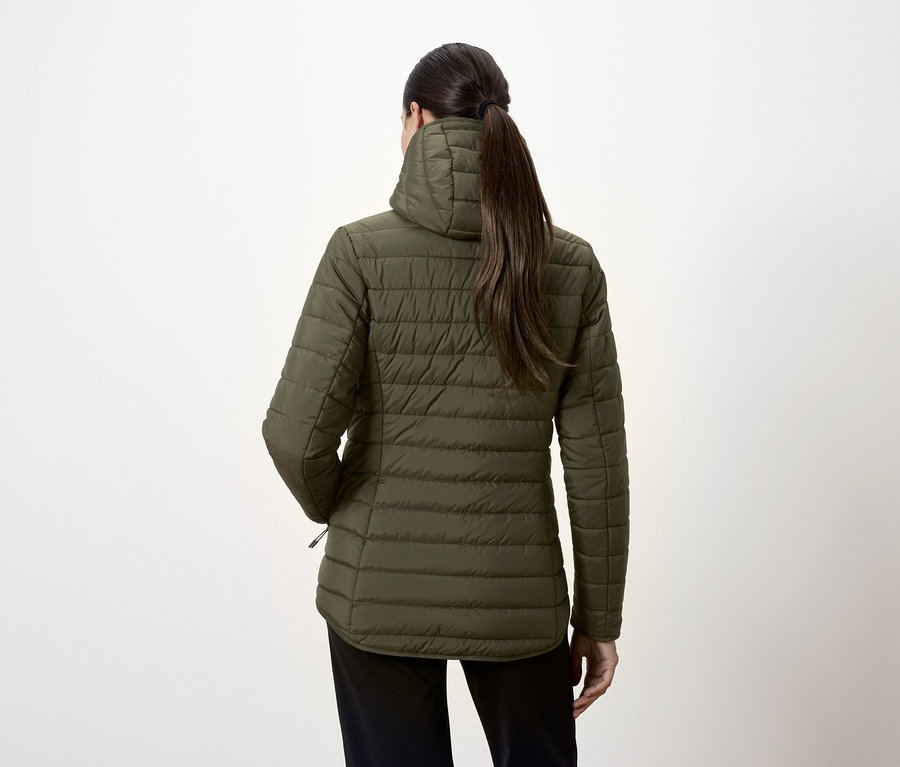 Pohľad zozadu na ženu v olivovozelenej prešívanej bunde a čiernych nohaviciach.