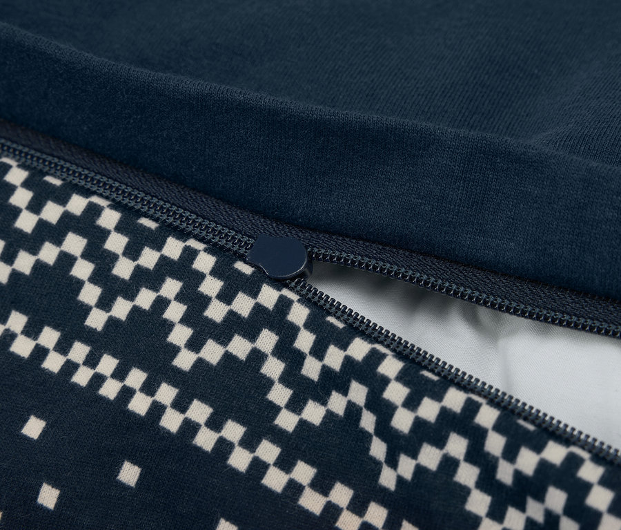 Detailný záber na čiastočne otvorenú tmavomodrú obliečku na prikrývku so zipsom a šachovnicovým vzorom.