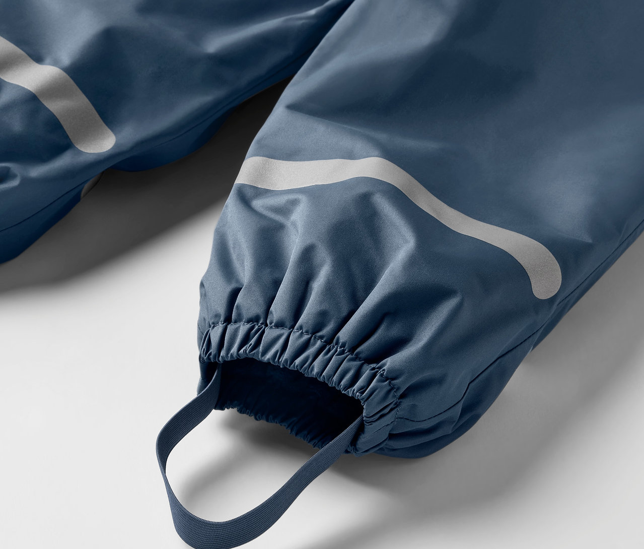 Detail modrých detských termo nohavíc do dažďa s reflexnými prvkami a elastickými lemami.