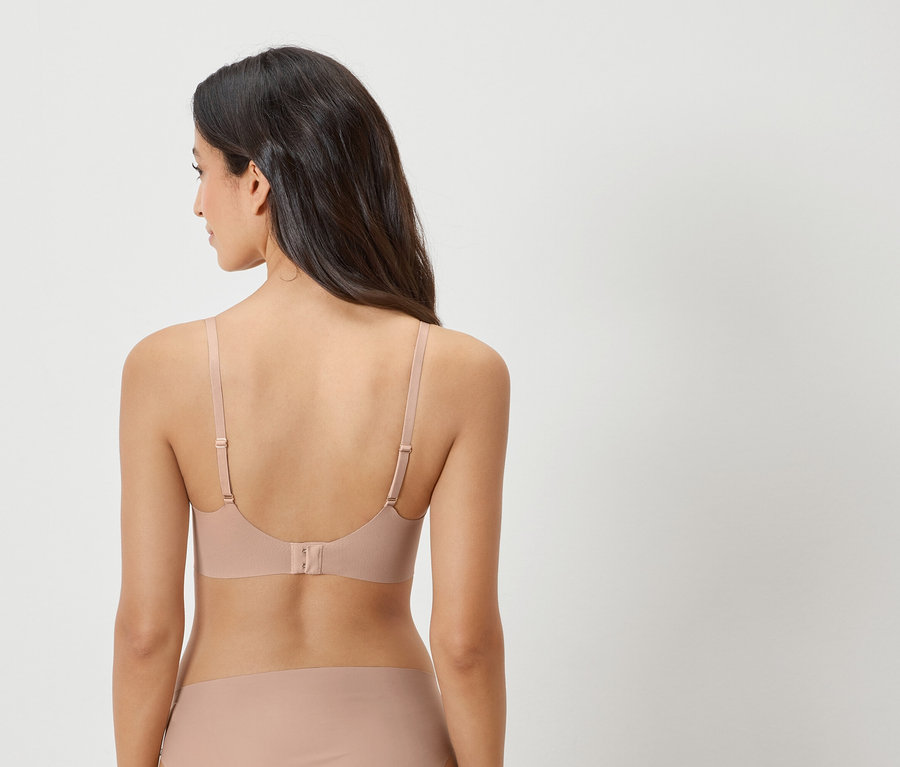 Pohľad zozadu na ženu s tmavými vlasmi v telovej podprsenke a zodpovedajúcich nohavičkách.