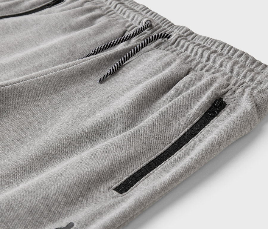 Detailný záber sivých teplákov so šnúrkou a vreckom na zips.
