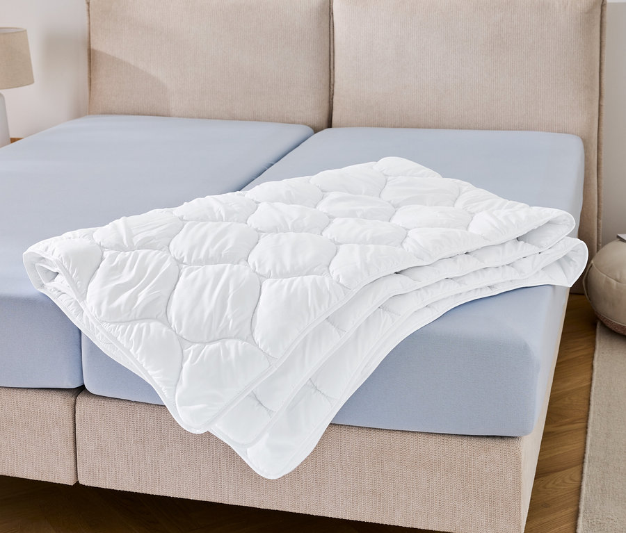 Na modrej plachte leží zložená prikrývka vhodná na vyváranie v nadmernej veľkosti.