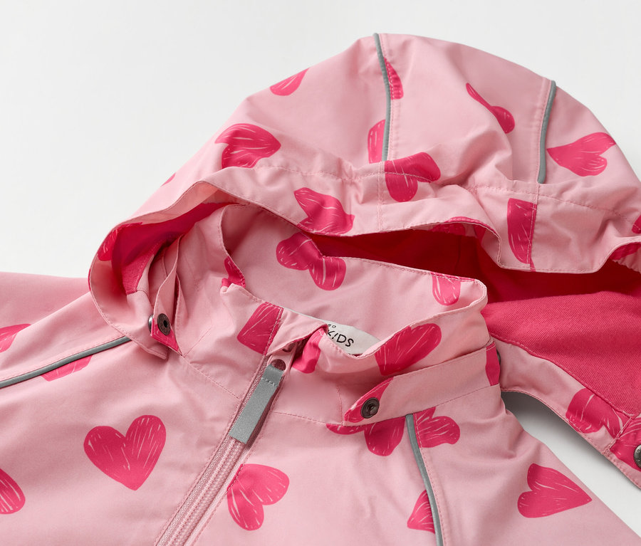 Detailný záber na svetloružovú detskú bundu s kapucňou a vzorom tmavoružových sŕdc.