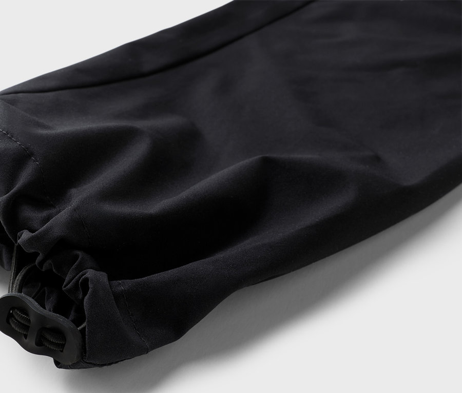 Detailný záber na nohavicu čiernych nohavíc s elastickým lemom a šnúrkou.