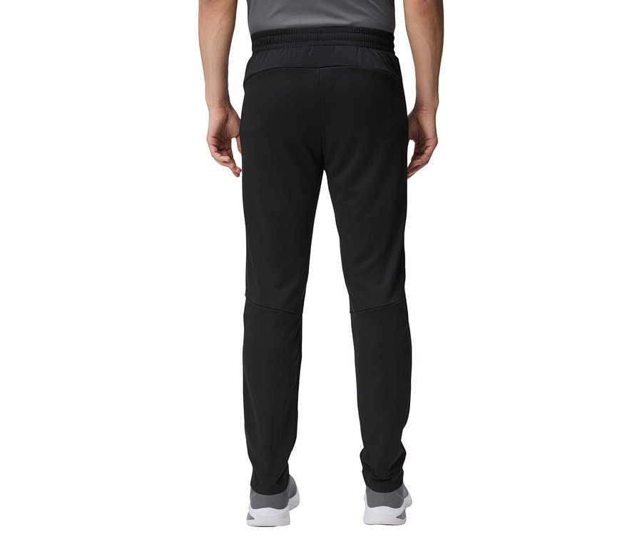 Detailný záber na zadnú časť osoby v čiernych teplákoch a sivých topánkach.