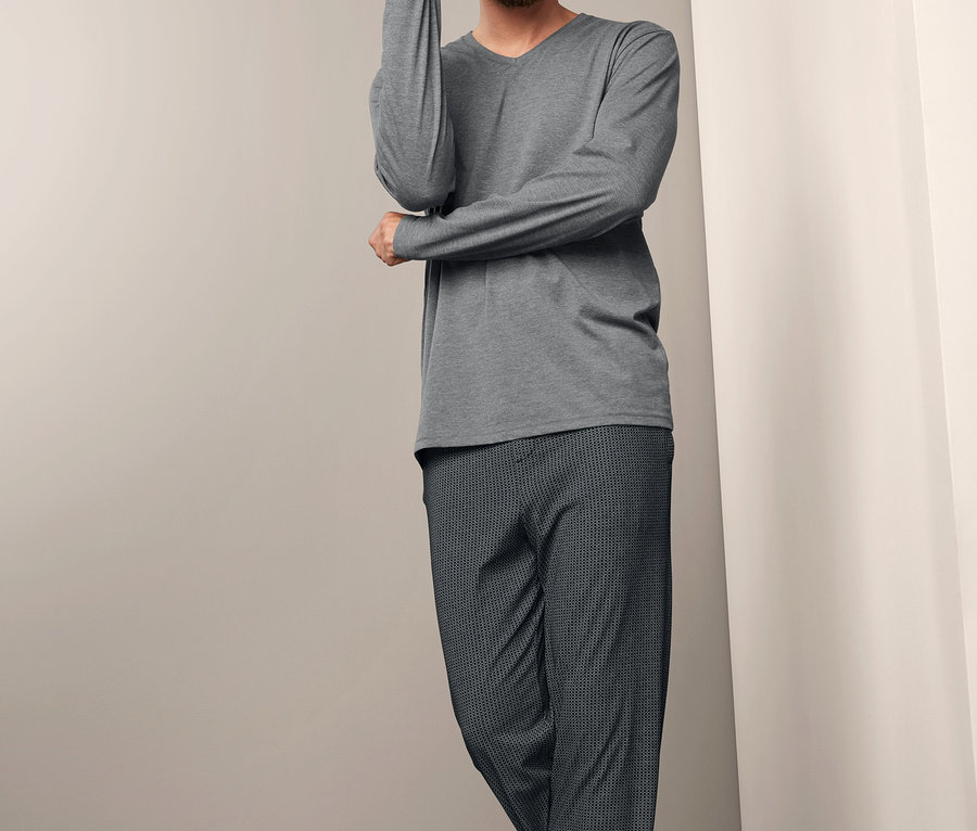 Muž pózuje v sivom pyžame.