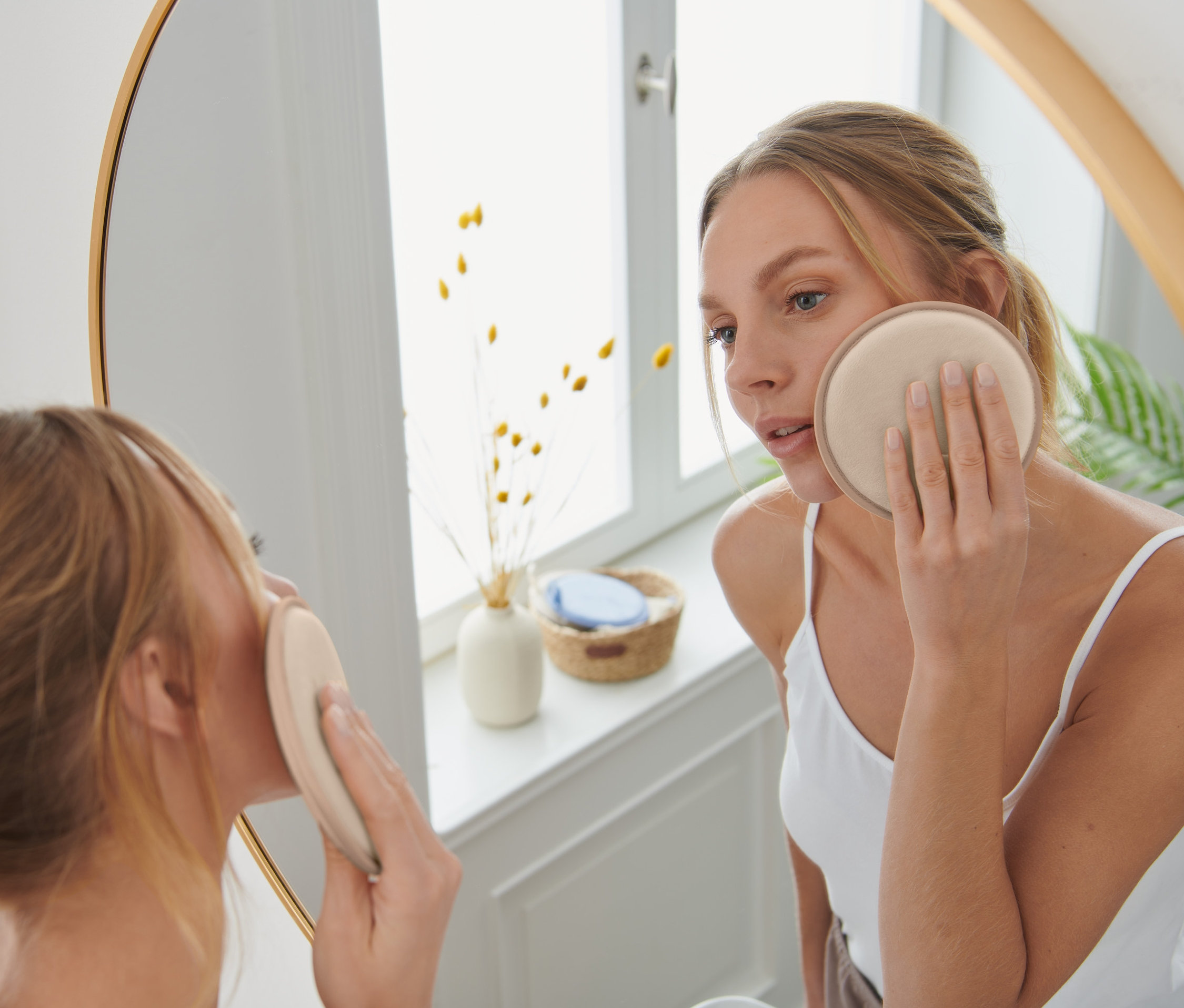 Žena si odličuje tvár pomocou opakovane použiteľného XL odličovacieho tampónu hnedej farby.