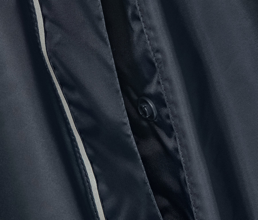 Detail modrého ponča do dažďa s gombíkom a reflexným pásikom.
