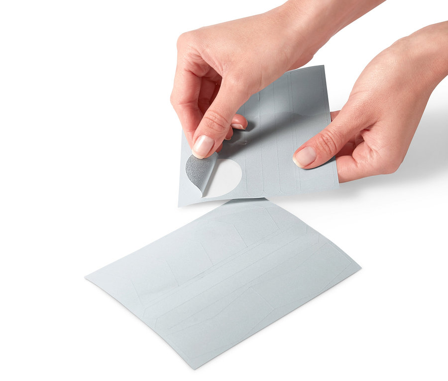 Ruky odlepujú reflexnú nálepku z archu reflexných nálepiek, 16 ks.