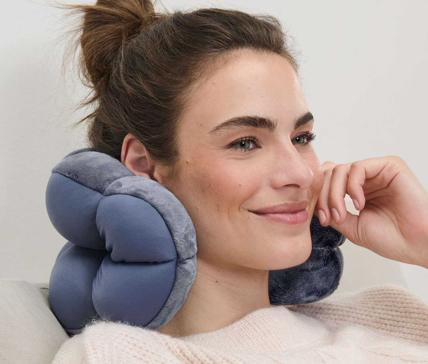 Žena sedí na pohovke s relaxačným vankúšom na krku.