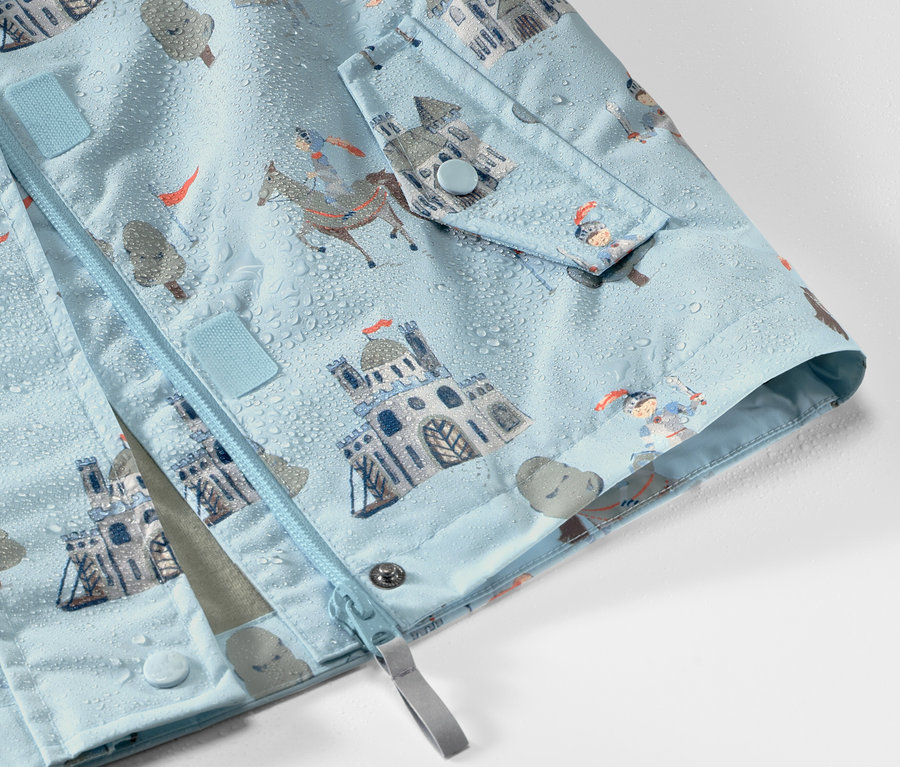 Detail detskej bundy do dažďa s motívom rytiera, na ktorej sú kvapky vody.