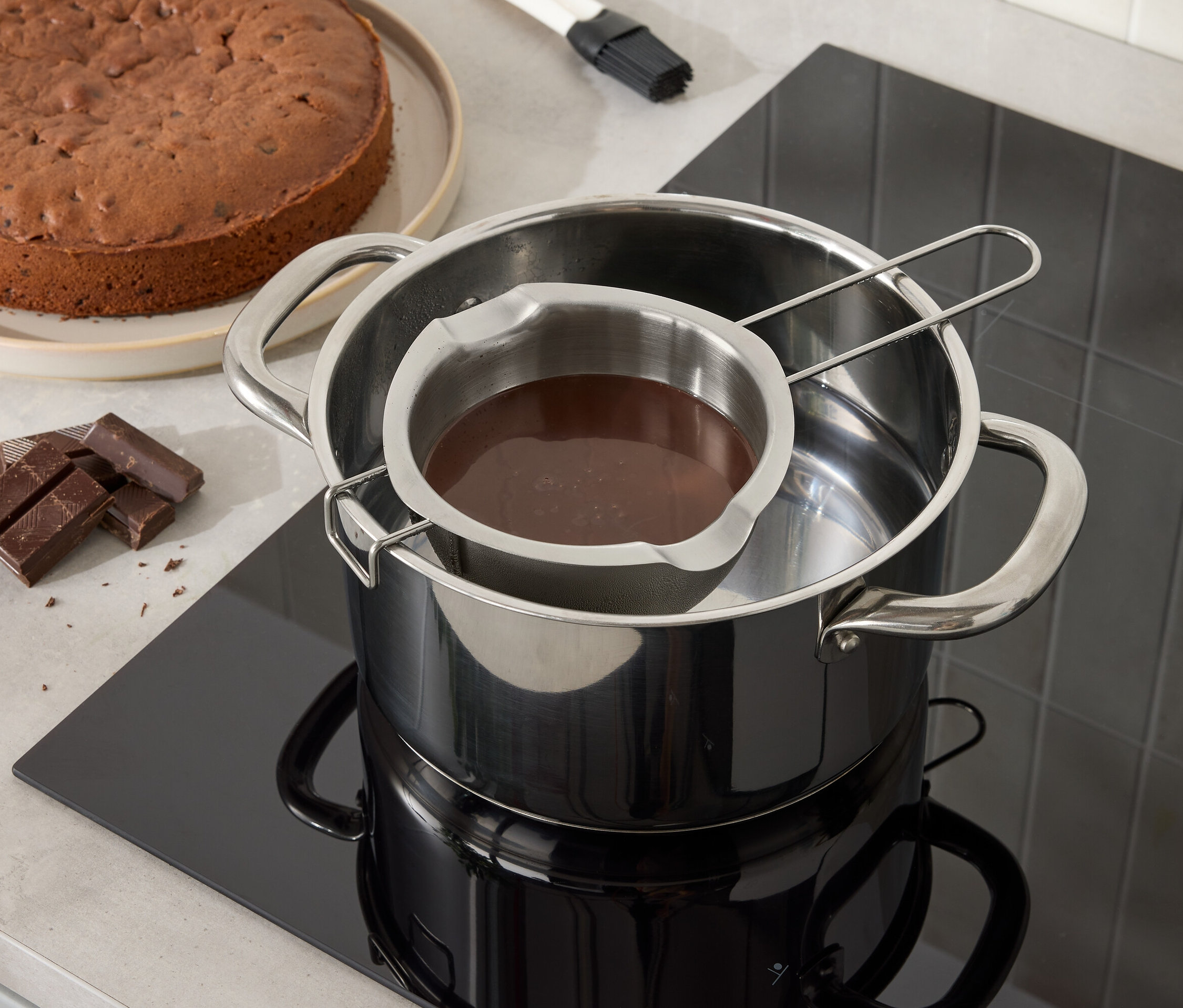 Čokoládová torta a čokoláda sa rozpúšťa v nerezovej miske nad hrncom s vodou.