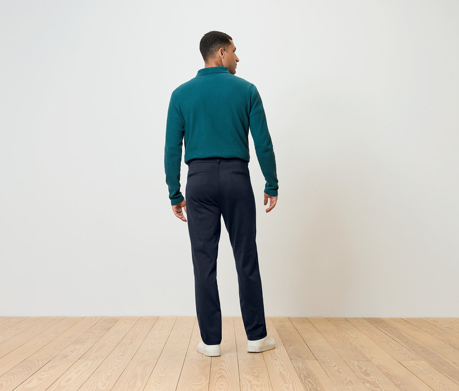 Muž otočený chrbtom má na sebe modré nohavice a zelený top s dlhým rukávom.